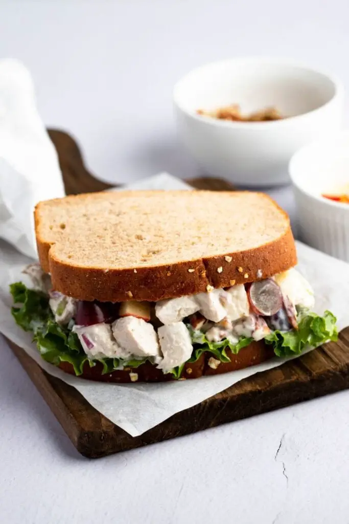 Receta de sándwich de ensalada de pollo de Arby.  La foto muestra un sándwich de ensalada de pollo casero servido en un plato de madera