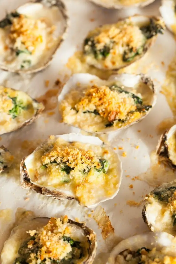 Las 25 mejores recetas de ostras para una cena gourmet fácil.  La foto muestra ostras cremosas con mantequilla con espinacas y pan rallado dorado en un plato