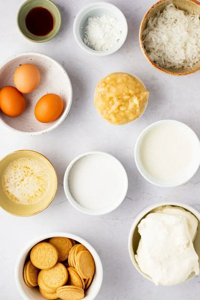 Pastel de queso con crema de plátano Ingredientes: vainilla, maicena, coco, huevos, puré de plátano, mantequilla derretida, azúcar, crema, oreos dorados y queso crema