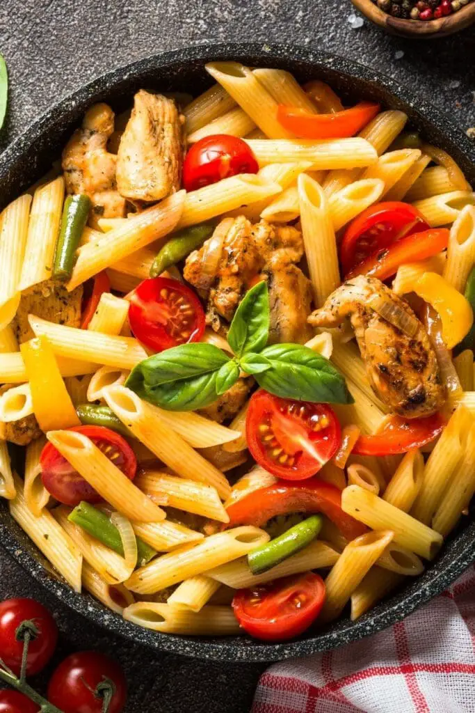 Pasta penne con pollo y tomates