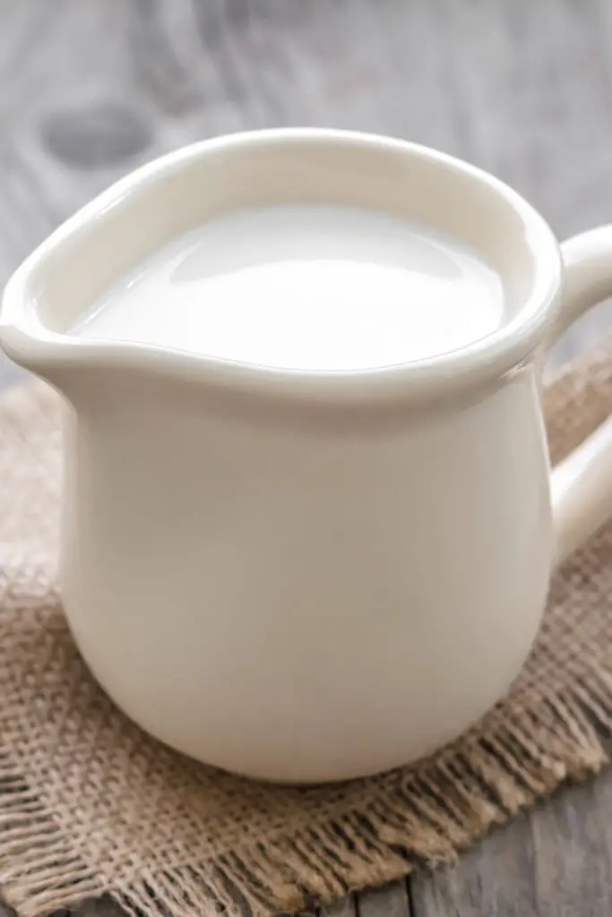 Indunstad mjölk i en vit porslinskanna