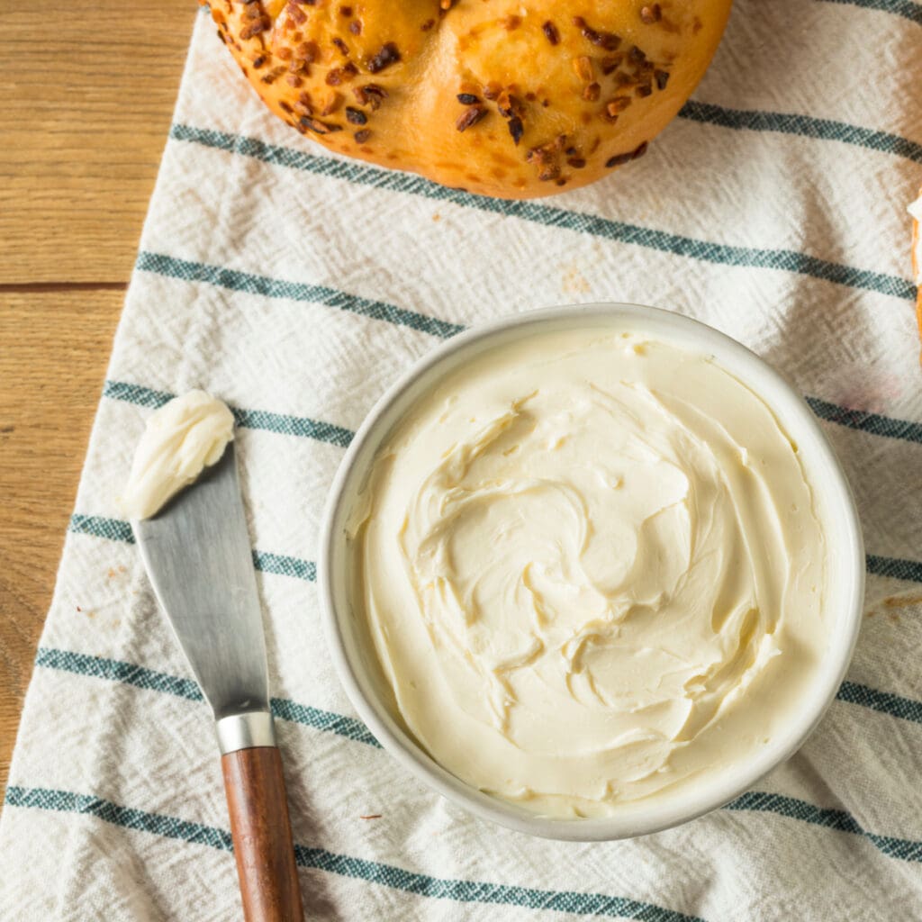 Queso crema bajo en grasa en un bol con un bagel al lado
