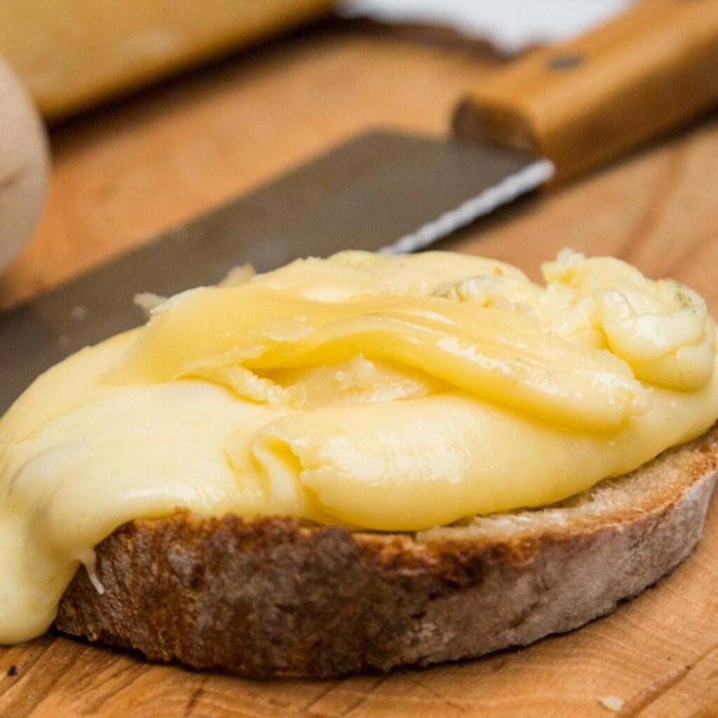 Queso raclette derretido encima de una rebanada de pan
