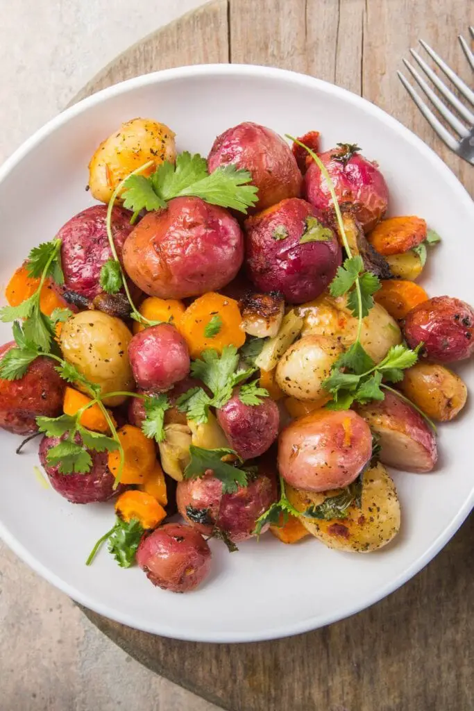 Geroosterde of gekookte gele en paarse aardappelen met wortelen