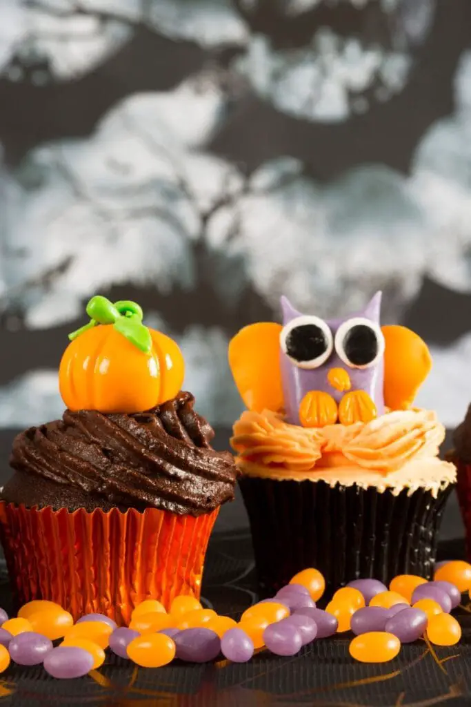 30 Halloween Potluck errezeta festa harrigarri baterako! Irudian: Halloween Cupcake gozoak kalabaza eta hontza diseinuarekin