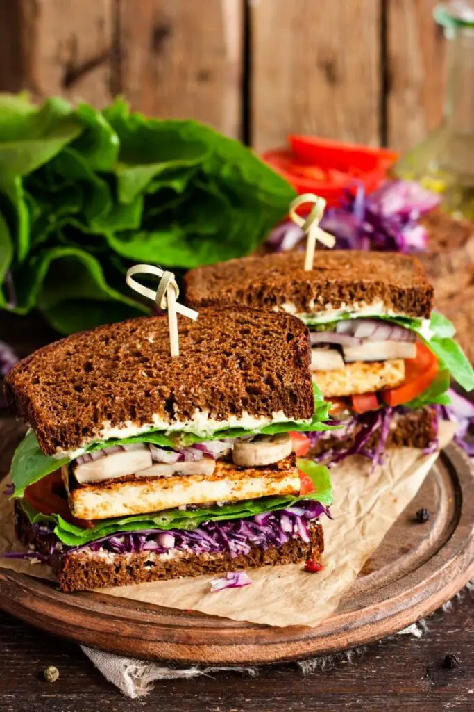 हार्दिक आणि निरोगी दुपारच्या जेवणासाठी 25 शाकाहारी सँडविच. चित्रात दाखवले आहे: टोफू आणि भाज्यांसह होममेड व्हेगन सँडविच