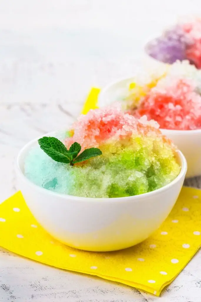 15 recetas de hielo raspado.  Se muestra en la imagen: Hielo raspado arcoíris casero en un tazón blanco