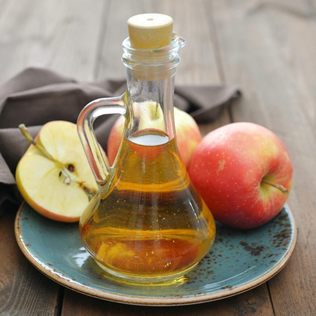 Vinagre de sidra de manzana en una jarra en un plato con manzanas