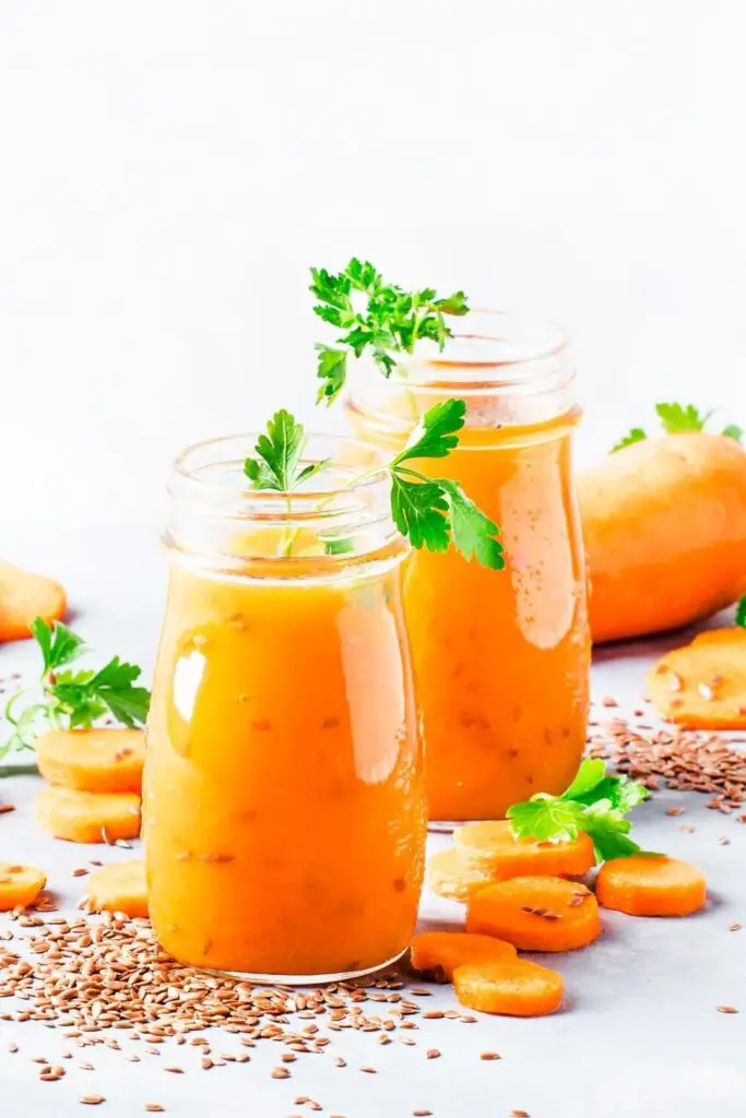 Batido de zanahoria fresco y saludable en una botella de vidrio con hierbas frescas