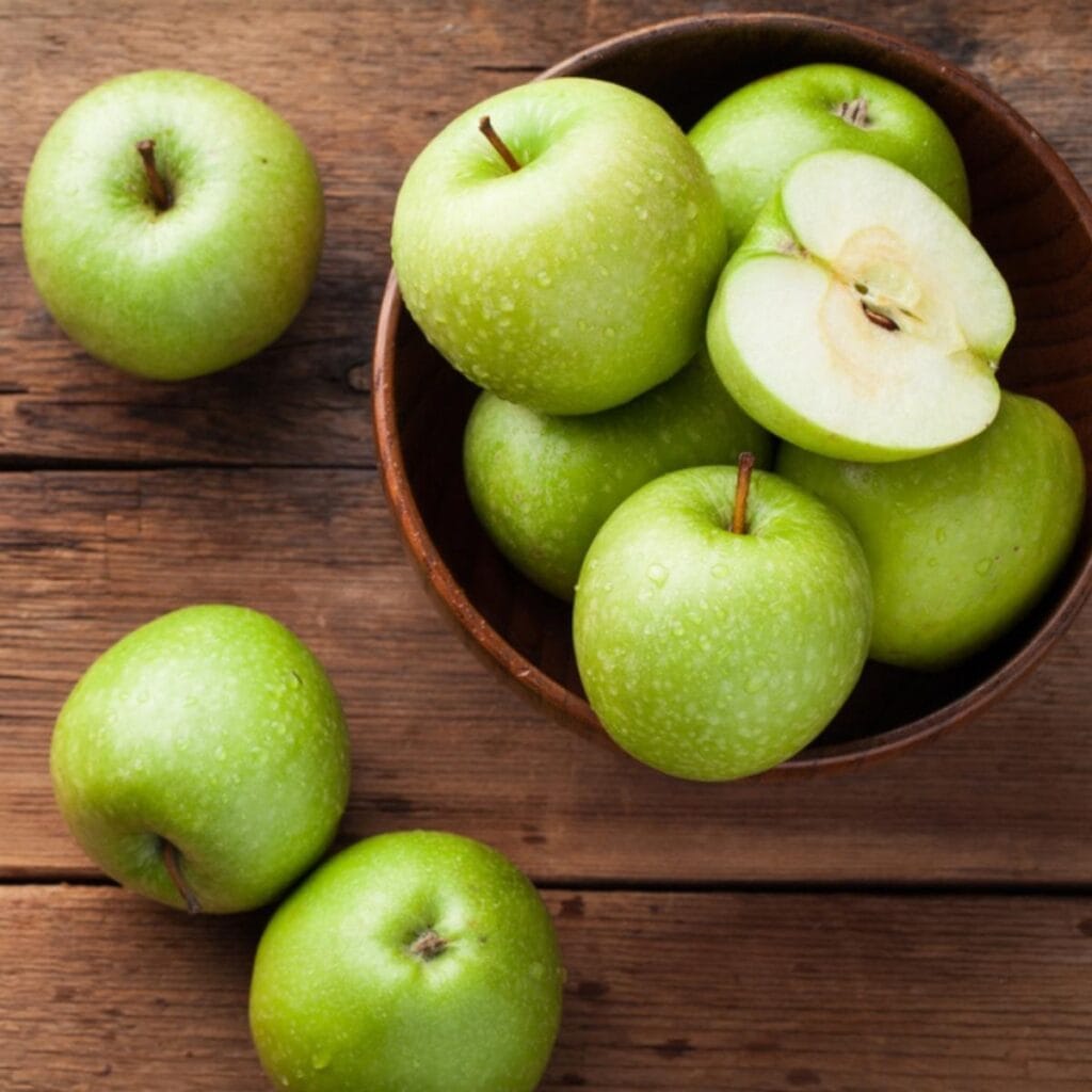 Manzanas verdes en una mesa de madera