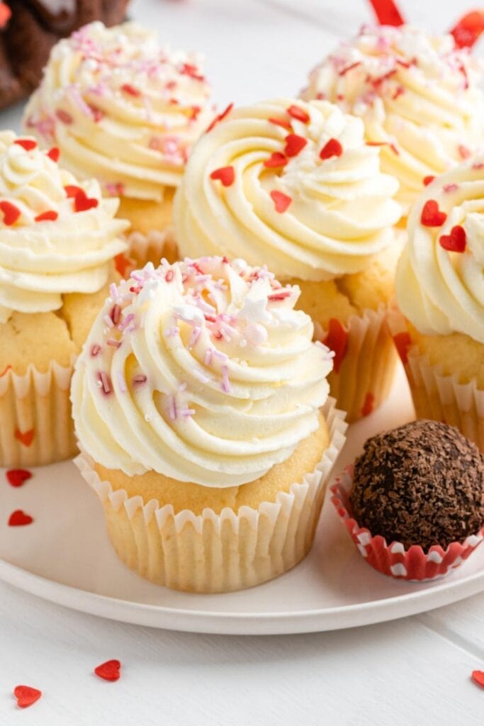 Cupcakes sin gluten de vainilla dulce con glaseado blanco y chispas de corazón en una placa blanca