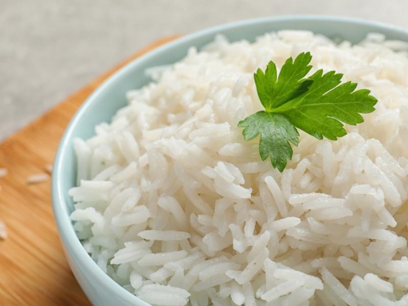 Варен дългозърнест бял ориз в зелена купа, покрит с листа от магданоз