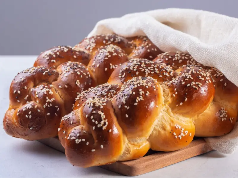 Värskelt küpsetatud challah leib, mis on pakitud valgesse riidesse