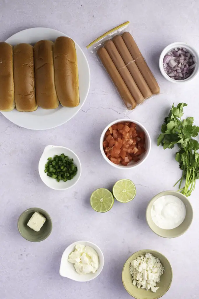 Përbërësit meksikan Hot Dogs: sallam, domate, lëng lime, qepë e kuqe, cilantro, qepë, salcë kosi dhe bukë