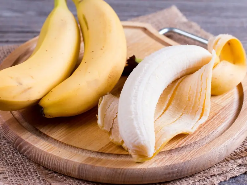 Plátanos pelados y enteros en una bandeja redonda de madera