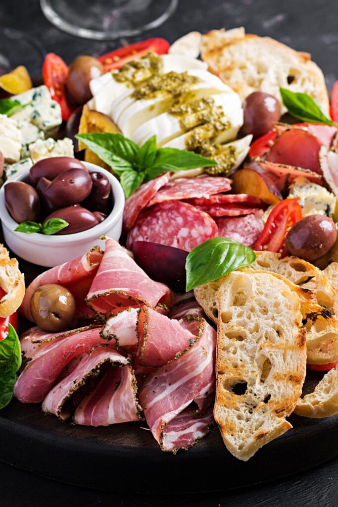 Assiette antipasti cù jambon, prosciutto, olive, pane, tomate è furmagliu