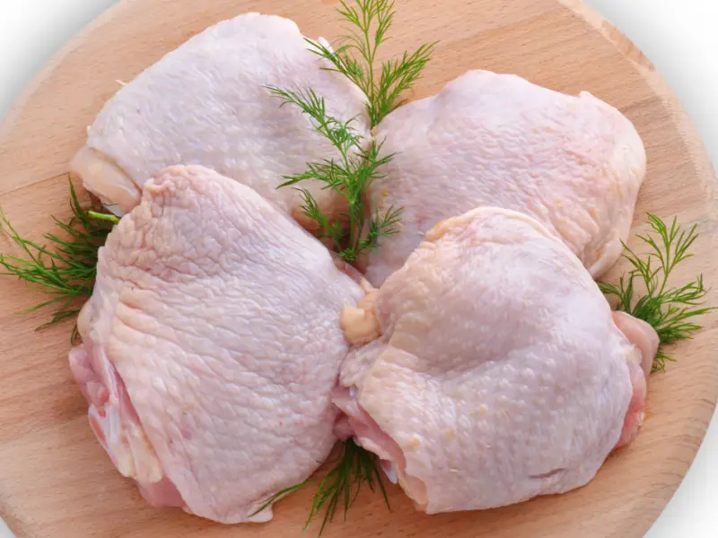 Raw Poulet Oberschenkel mat Thymian op engem ronnen Schneidebrett