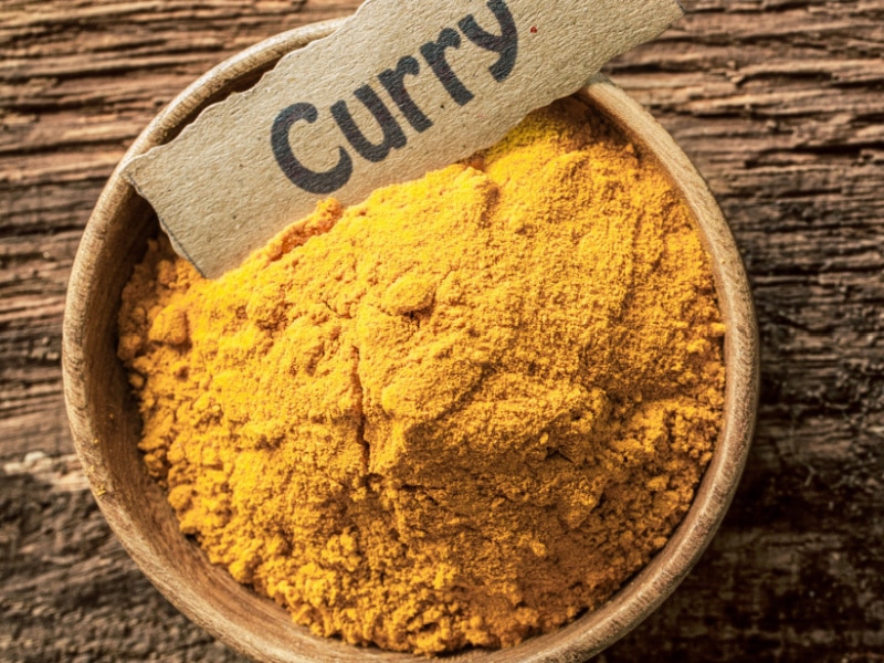 Curry en polvo en un recipiente de madera con etiqueta