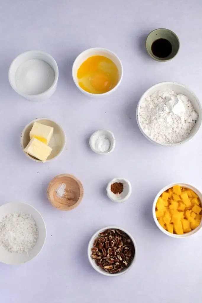 Ingredientes del pan de mango: harina para todo uso, bicarbonato de sodio, canela molida, sal, huevos, mantequilla ablandada, azúcar granulada, extracto de vainilla, mango, coco y nueces