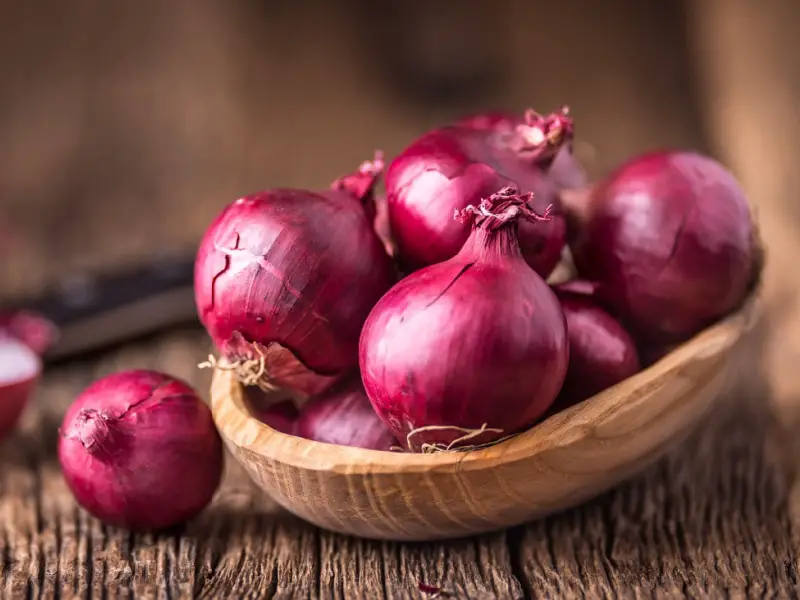 Cebollas rojas en un cuenco de madera