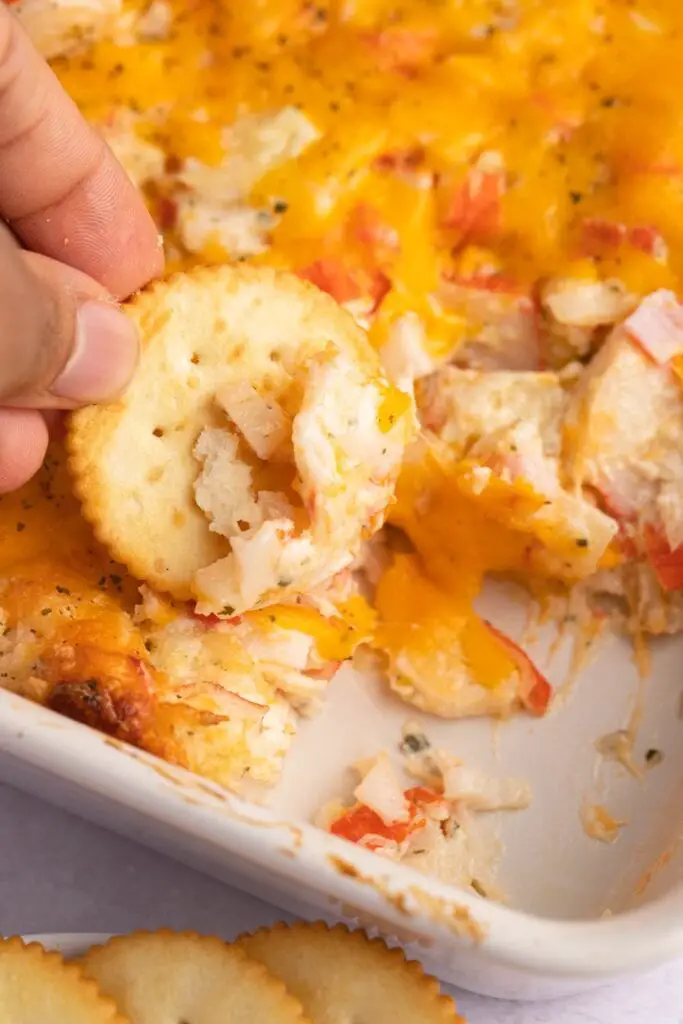 Sumergir una galleta en una cazuela de cangrejo con queso