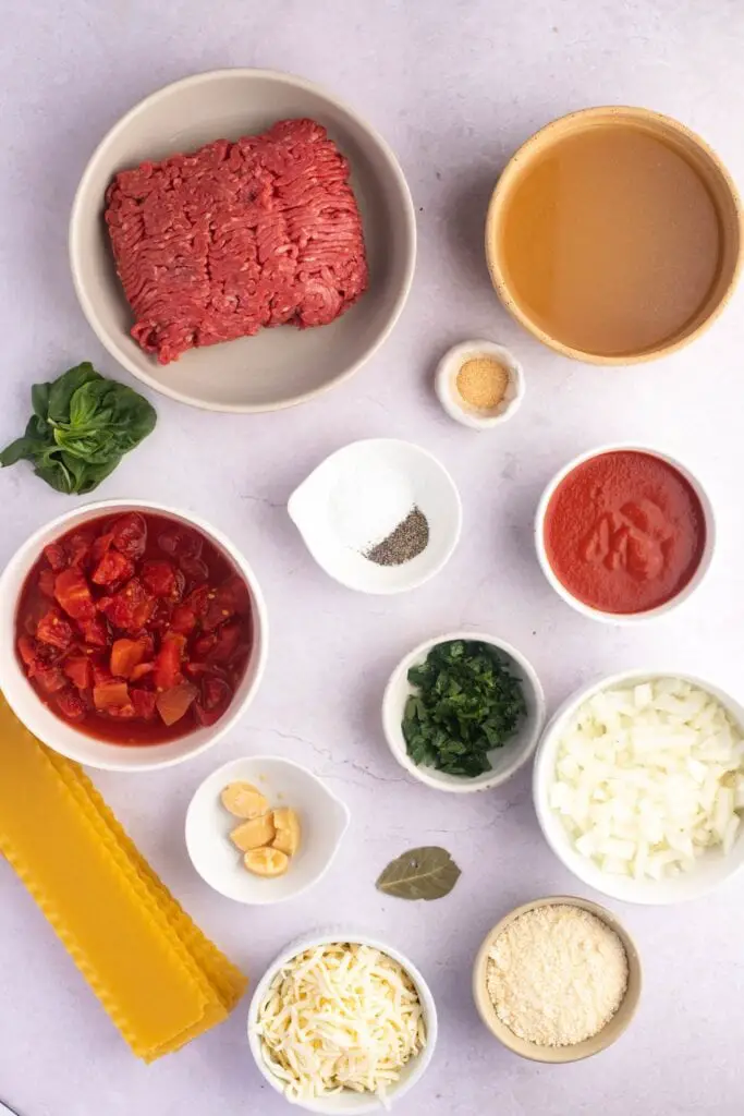 Ingredientes de sopa de lasaña Crockpot: carne molida, ajo en polvo, caldo de pollo, tomates cortados en cubitos, perejil, fideos de lasaña, albahaca y queso