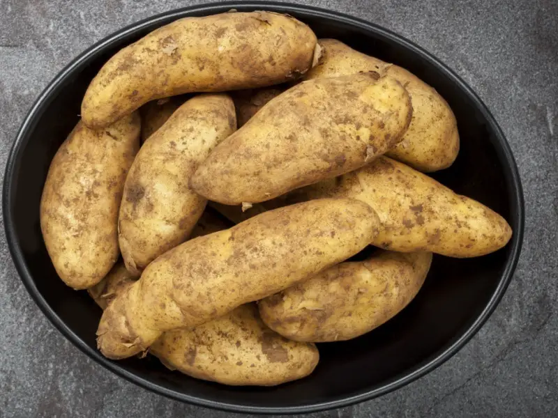 Manojo de papas alargadas en un plato de metal negro