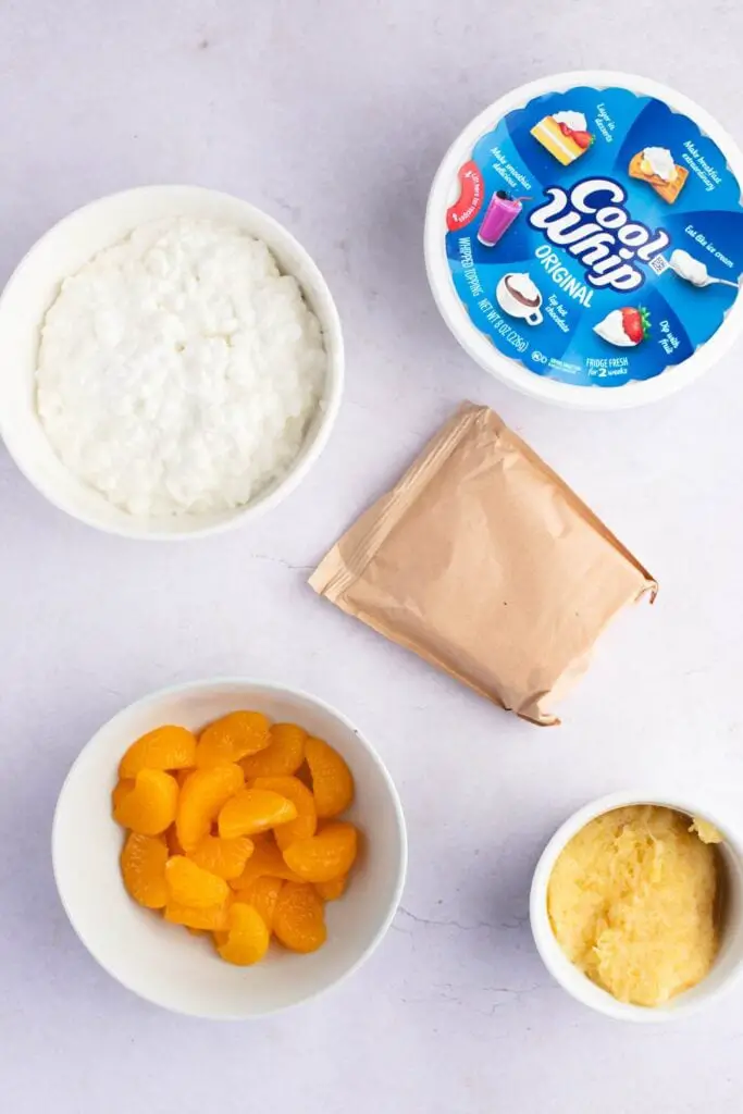 Ingredientes de la ensalada de gelatina de naranja: mandarina, piña triturada, gelatina de naranja, requesón, cobertura batida esponjosa