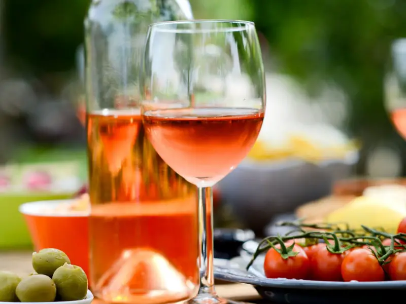 Una botella y una copa de vino rosado