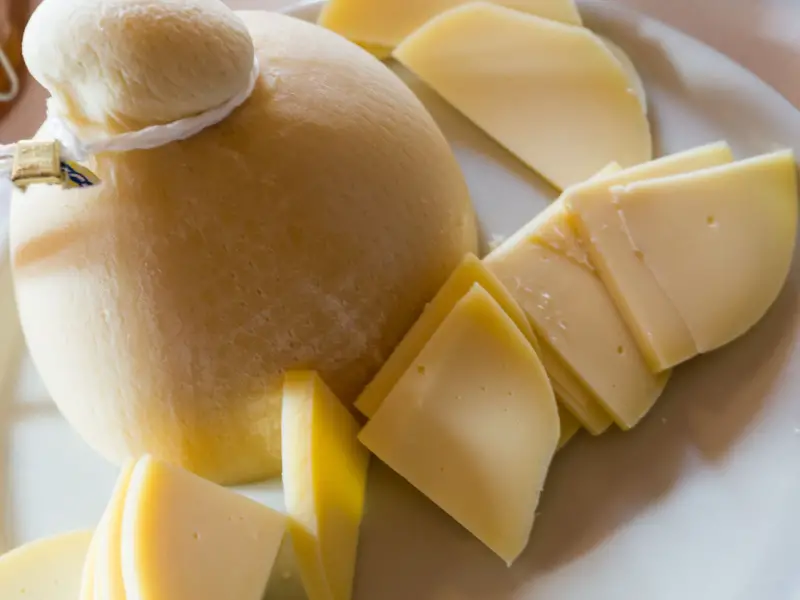 Queso provolone entero y rebanado en un plato blanco