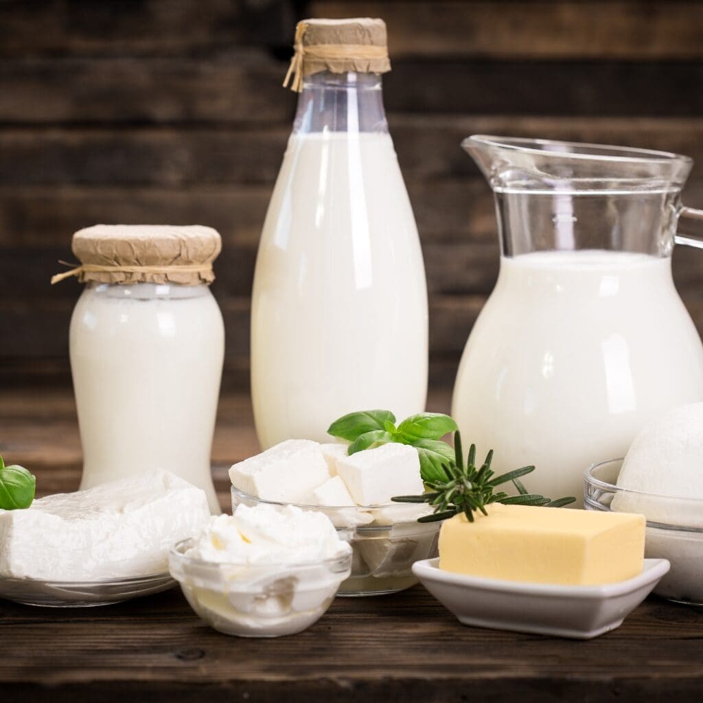 Frascos de leche, mitad y mitad, y crema sobre una mesa con queso crema, mantequilla, tofu y mozzarella