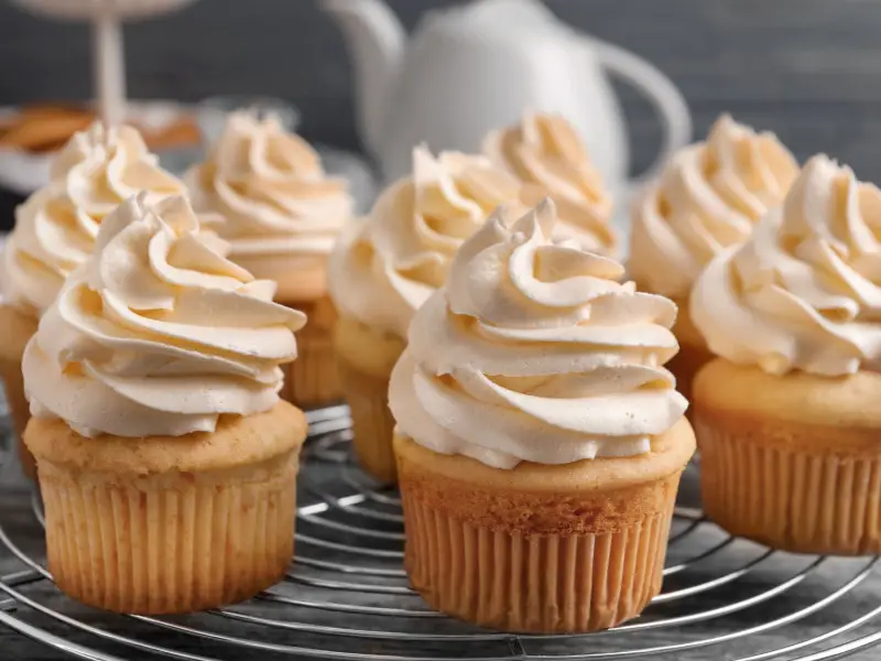 Pastelitos cubiertos con crema de mantequilla en una rejilla para enfriar