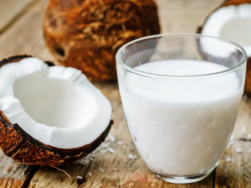 Medio coco y un vaso de leche de coco