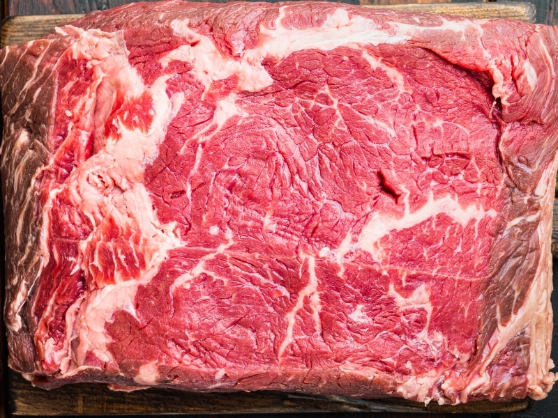 Biftek me fileto të papërpunuar në një dërrasë prej druri