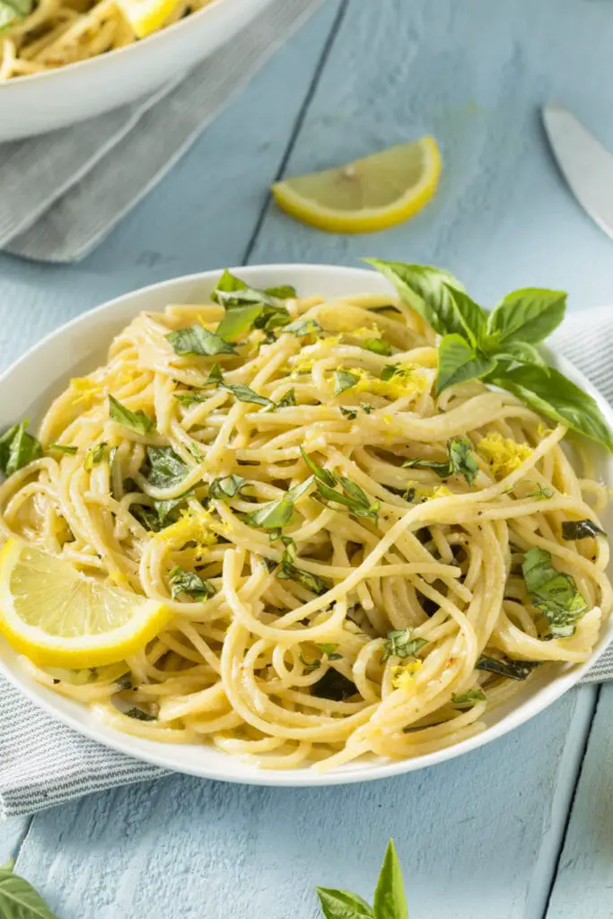 Espaguetis al limón adornados con albahaca fresca y rodajas de limón