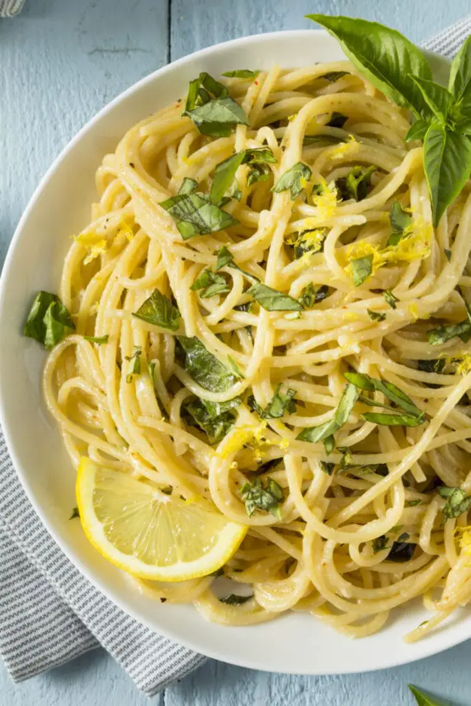 Spaghetti al limone guarniti con scorza di limone e foglie di basilico fresco