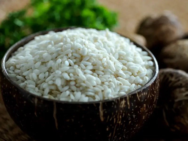 Champiñones enteros y arroz risotto crudo en un bol de coco