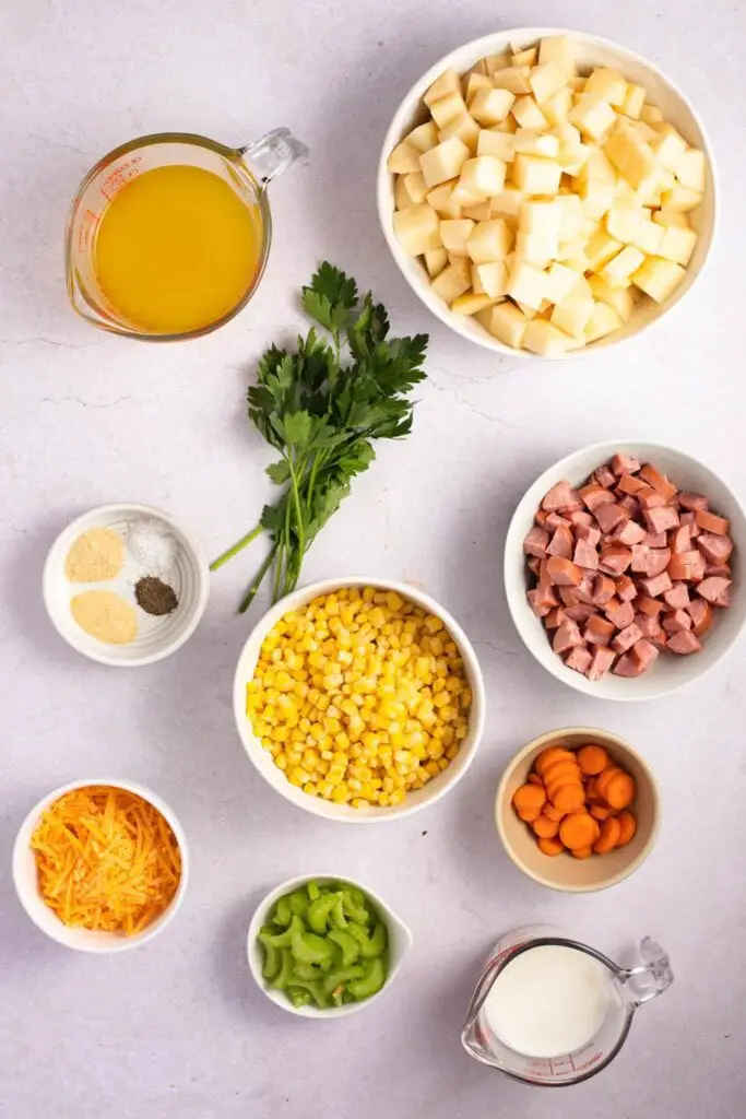 Ingredientes de la sopa de patatas con salchicha: kielbasa ahumada, patatas, maíz congelado, caldo de pollo, apio, zanahorias, condimentos, leche, queso cheddar y perejil