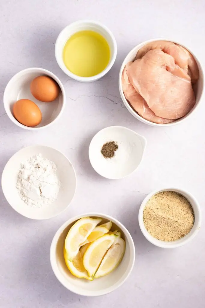Ingredientes de milanesa de pollo: harina, huevos, sal kosher, pimienta negra, pan rallado, pollo deshuesado, aceite vegetal y limón