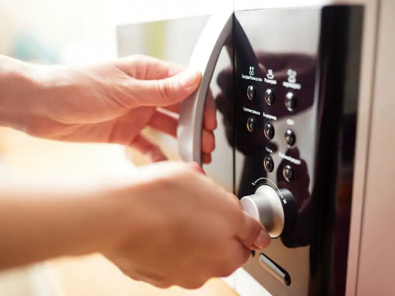 Person adjusting the temperature of the microwave oven