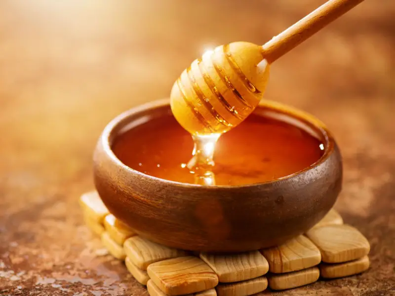 Goteo de miel en un cuenco de madera