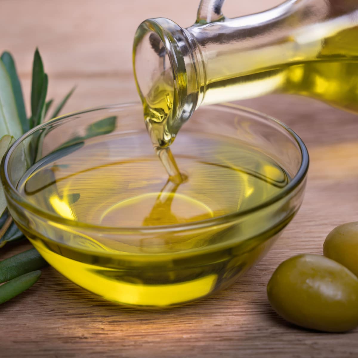 Un bol d'huile d'olive et d'olives sur une table en bois